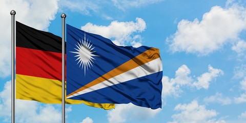 Germany and Marshall Islands flag waving in the wind against white cloudy blue sky together. Diplomacy concept, international relations.