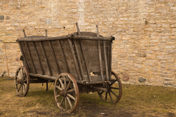 Fototapeta na wymiar An old horse-drawn carriage stands near a stone wall.