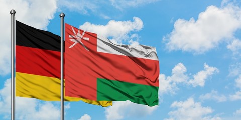 Germany and Oman flag waving in the wind against white cloudy blue sky together. Diplomacy concept, international relations.