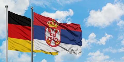 Germany and Serbia flag waving in the wind against white cloudy blue sky together. Diplomacy concept, international relations.