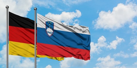 Germany and Slovenia flag waving in the wind against white cloudy blue sky together. Diplomacy concept, international relations.