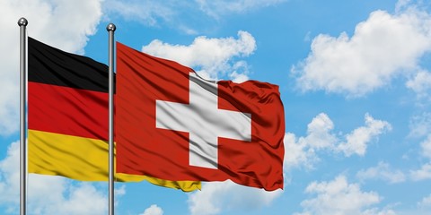 Germany and Switzerland flag waving in the wind against white cloudy blue sky together. Diplomacy concept, international relations.