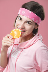 Cute white caucasian girl with a smile bites an orange. Close-up portrait of a girl with an orange.