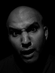 closeup black and white portrait photo of a bald headed brown making a funny face. A face of stunt, shocked and confused look