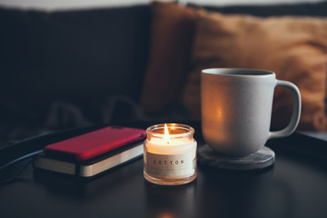 Enjoying warm winter evening at home with cup of tea and candle on the table. After work, offline...