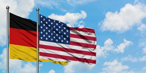 Germany and United States flag waving in the wind against white cloudy blue sky together. Diplomacy concept, international relations.