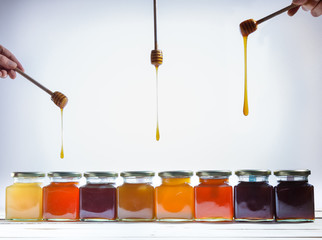 jars of honey, and sticks spilling honey on white background