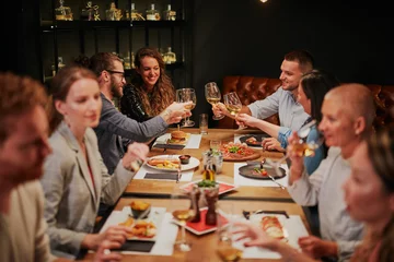 Poster Group of best friends sitting in restaurant, having dinner, drinking wine and having fun. © chika_milan