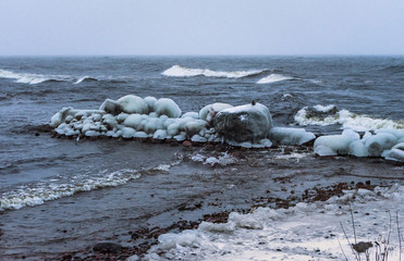 breakwater in ice in dark waves of the winter sea