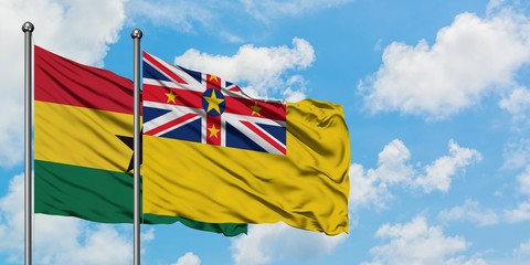 Ghana and Niue flag waving in the wind against white cloudy blue sky together. Diplomacy concept, international relations.