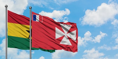 Ghana and Wallis And Futuna flag waving in the wind against white cloudy blue sky together. Diplomacy concept, international relations.