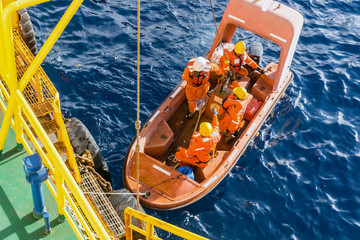 Fast rescue craft being deployed from a construction barge at oil field