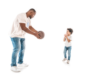 handsome african american man showing basketball to adorable son on white background