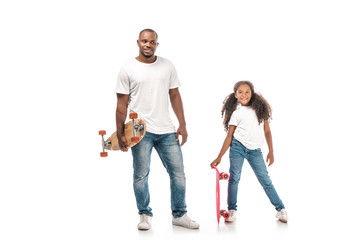 Handsome African American man with longboard standing near daughter holding skate on white background