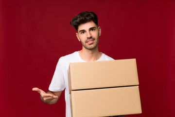 Young man over isolated background holding a box to move it to another site