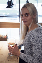 girl in a cafe at a table with a glass of wine near the window on the stairs