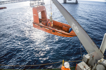 Fast rescue craft being hoisted onto a construction barge after performing an emergency drill...