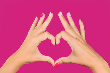 Closeup point of view photography of hands of beautiful young woman making heart gesture isolated...