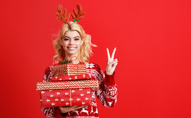 happy young cheerful girl laughs and jumps in christmas hat and with  gift on  red   background.