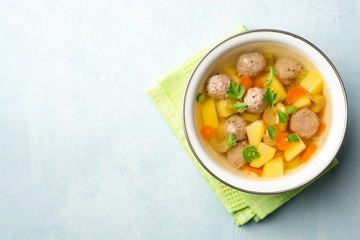 Soup with meatballs and vegetables in bowl on concrete background. Top view. Copy space.