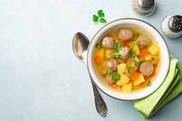 Soup with meatballs and vegetables in bowl on concrete background. Top view. Copy space.