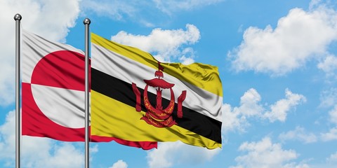 Greenland and Brunei flag waving in the wind against white cloudy blue sky together. Diplomacy concept, international relations.
