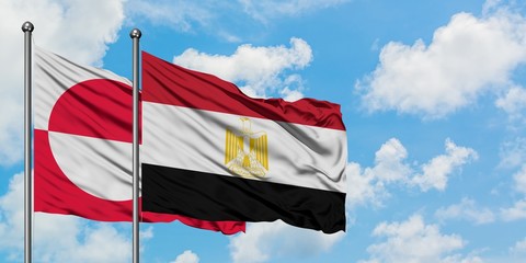Greenland and Egypt flag waving in the wind against white cloudy blue sky together. Diplomacy concept, international relations.