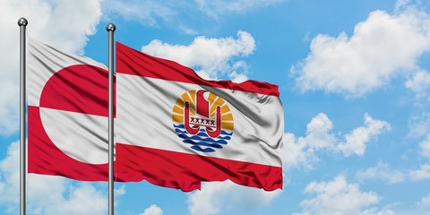 Greenland and French Polynesia flag waving in the wind against white cloudy blue sky together. Diplomacy concept, international relations.