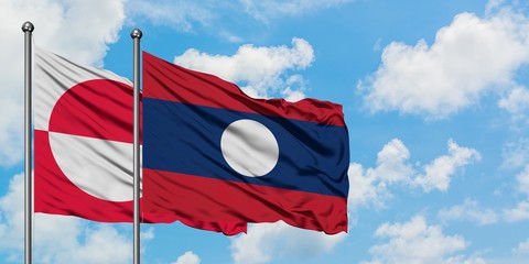 Greenland and Laos flag waving in the wind against white cloudy blue sky together. Diplomacy concept, international relations.