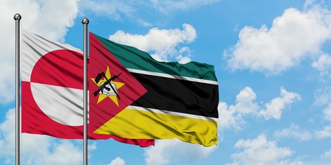 Greenland and Mozambique flag waving in the wind against white cloudy blue sky together. Diplomacy concept, international relations.