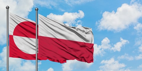 Greenland and Poland flag waving in the wind against white cloudy blue sky together. Diplomacy concept, international relations.