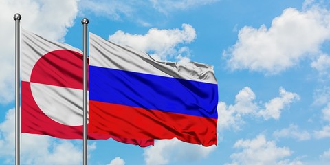 Greenland and Russia flag waving in the wind against white cloudy blue sky together. Diplomacy concept, international relations.
