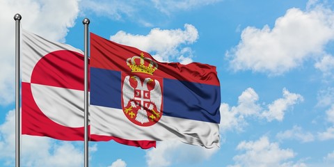 Greenland and Serbia flag waving in the wind against white cloudy blue sky together. Diplomacy concept, international relations.