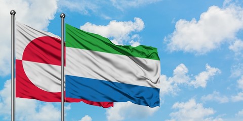 Greenland and Sierra Leone flag waving in the wind against white cloudy blue sky together. Diplomacy concept, international relations.