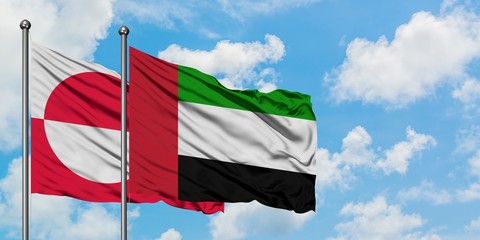 Greenland and United Arab Emirates flag waving in the wind against white cloudy blue sky together. Diplomacy concept, international relations.