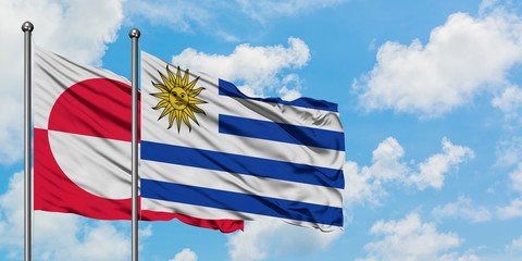 Greenland and Uruguay flag waving in the wind against white cloudy blue sky together. Diplomacy concept, international relations.