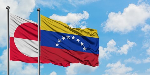 Greenland and Venezuela flag waving in the wind against white cloudy blue sky together. Diplomacy concept, international relations. © sezerozger