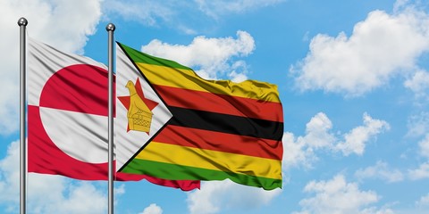 Greenland and Zimbabwe flag waving in the wind against white cloudy blue sky together. Diplomacy concept, international relations.