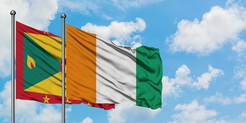 Grenada and Cote D'Ivoire flag waving in the wind against white cloudy blue sky together. Diplomacy concept, international relations.