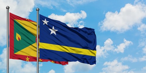 Grenada and Curacao flag waving in the wind against white cloudy blue sky together. Diplomacy concept, international relations.