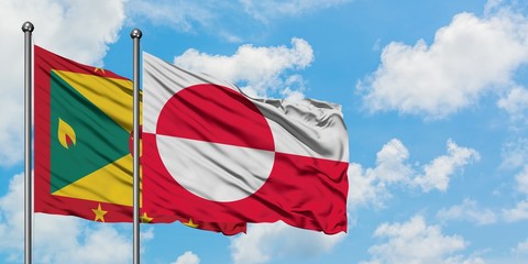 Grenada and Greenland flag waving in the wind against white cloudy blue sky together. Diplomacy concept, international relations.