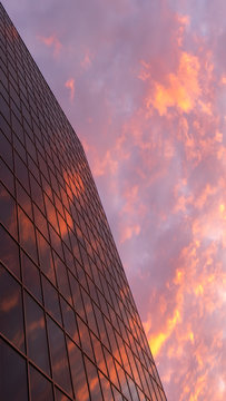 Abstract view of a skyscraper with a reflection of the evening sky and red clouds. Copy space. Beautiful geometric city view. Vertical frame for Instagram stories.