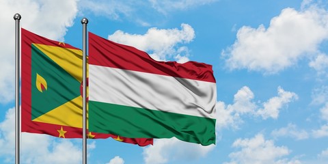 Grenada and Hungary flag waving in the wind against white cloudy blue sky together. Diplomacy concept, international relations.