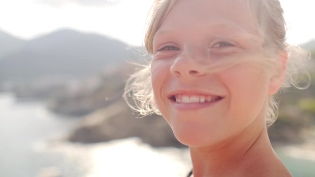 portrait of an authentic smiling young child with sunset background on the beach.