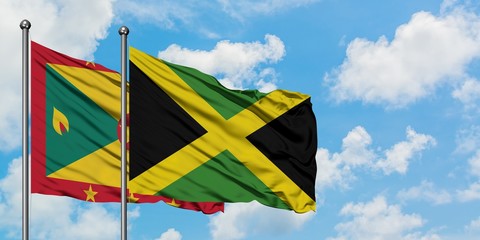 Grenada and Jamaica flag waving in the wind against white cloudy blue sky together. Diplomacy concept, international relations.