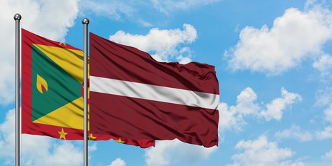 Grenada and Latvia flag waving in the wind against white cloudy blue sky together. Diplomacy concept, international relations.