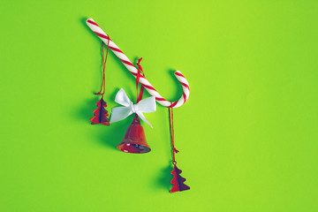 Composition of  christmas minimalism on a green background. Red Christmas tree toys and bells and candy cane.