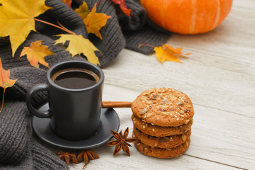 Grey cup of coffee, stack of cookies, spices, plaid, yellow maple leaves, orange pumpkin on white wooden table. Autumn menu concept. Fall, expresso, cinnamon