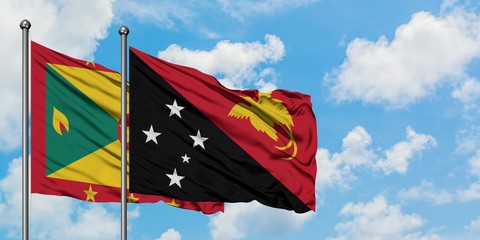 Grenada and Papua New Guinea flag waving in the wind against white cloudy blue sky together. Diplomacy concept, international relations.
