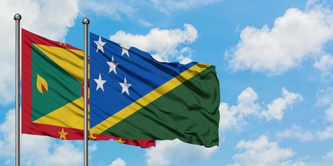 Grenada and Solomon Islands flag waving in the wind against white cloudy blue sky together. Diplomacy concept, international relations.